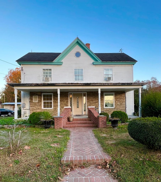 view of front of home with a porch, stone siding, and a chimney