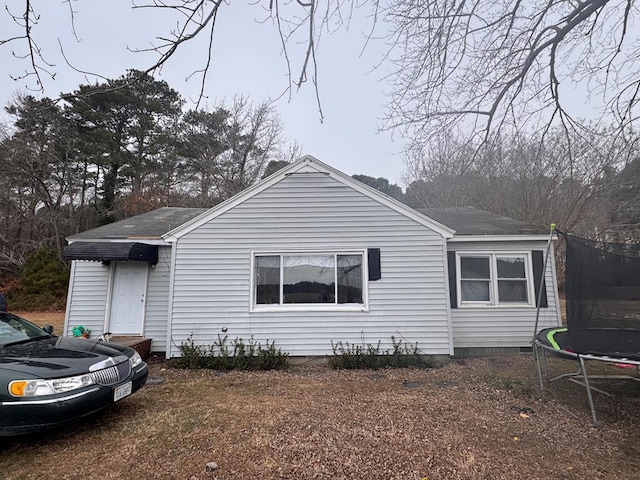 view of front of property with a shingled roof and a trampoline