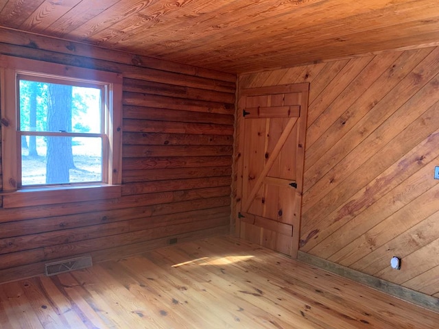 unfurnished room with light wood-type flooring, wood ceiling, and wooden walls