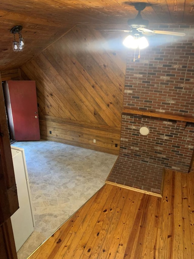 unfurnished living room featuring ceiling fan, wood walls, and light hardwood / wood-style floors