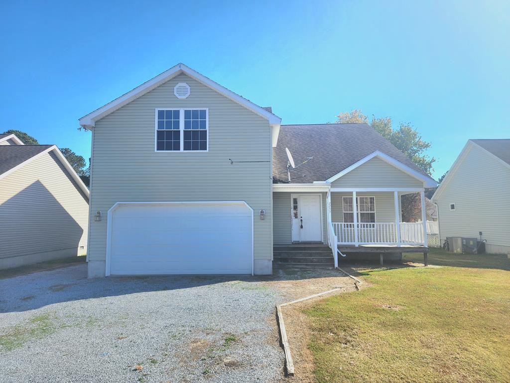 view of front of house with a porch, a garage, and a front lawn