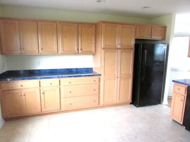 kitchen with black refrigerator and light brown cabinets