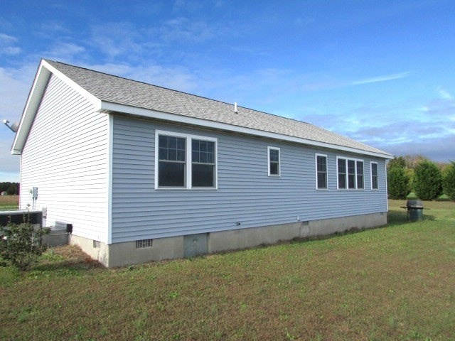 view of side of home with a yard and central AC