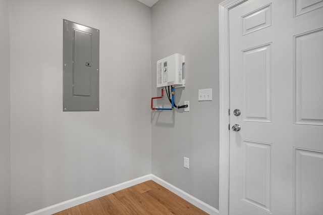 laundry area featuring baseboards, wood finished floors, and electric panel