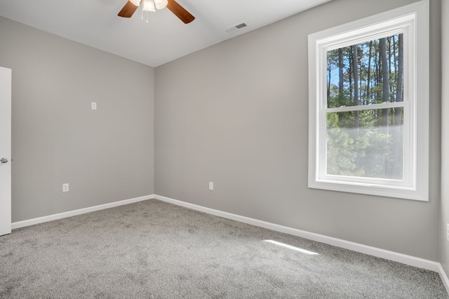 carpeted spare room featuring baseboards, ceiling fan, and visible vents