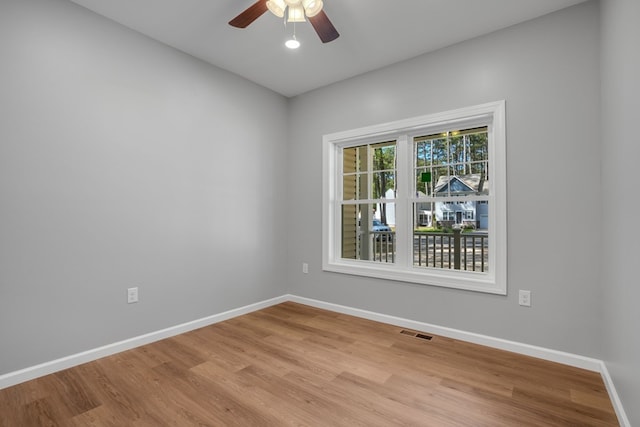 spare room featuring baseboards, visible vents, and wood finished floors