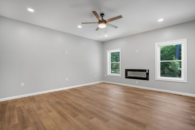 unfurnished living room with a ceiling fan, visible vents, a wealth of natural light, and light wood-style flooring