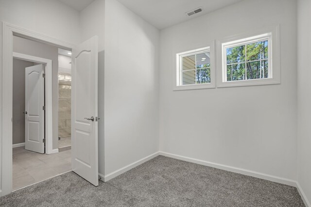 interior space with baseboards, visible vents, light carpet, and a healthy amount of sunlight