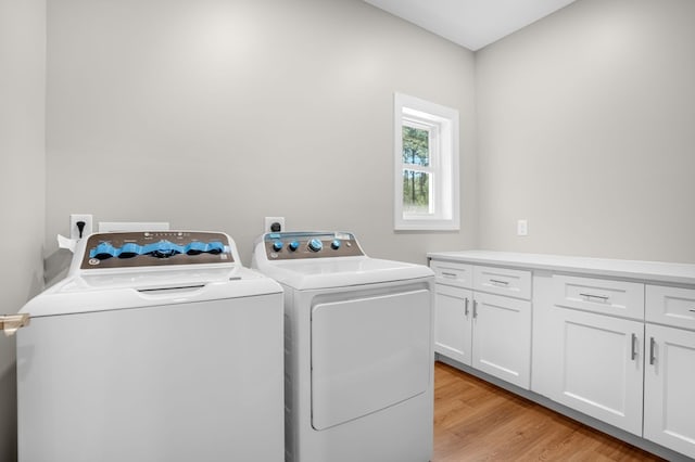 washroom with light wood-style floors, independent washer and dryer, and cabinet space