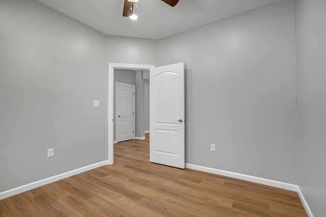 unfurnished room with a ceiling fan, baseboards, and light wood-style flooring
