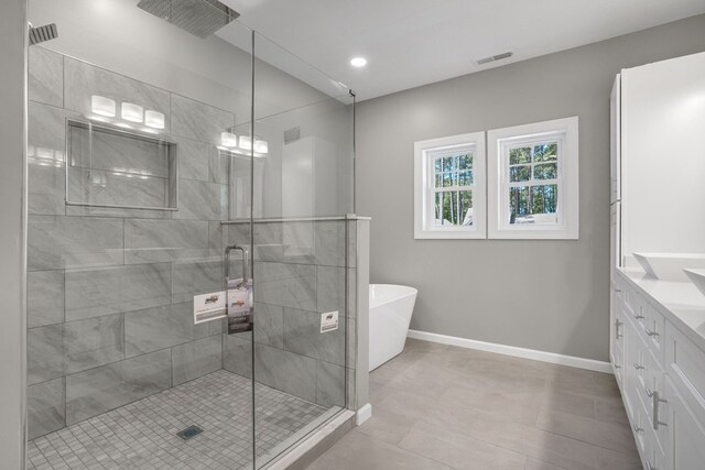 full bathroom with visible vents, a freestanding bath, a stall shower, baseboards, and vanity