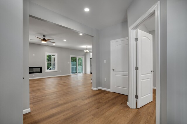 interior space featuring light wood-type flooring, recessed lighting, baseboards, and ceiling fan with notable chandelier