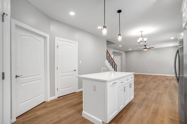 kitchen featuring light wood-style floors, white cabinets, a notable chandelier, and decorative light fixtures