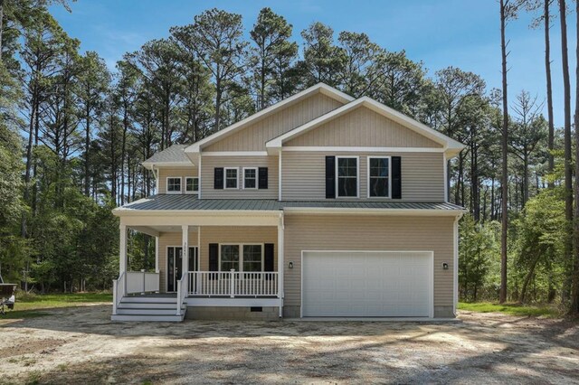 view of front of home with an attached garage, dirt driveway, covered porch, and metal roof