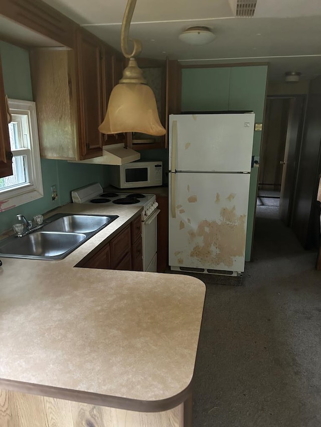 kitchen with kitchen peninsula, white appliances, sink, and hanging light fixtures