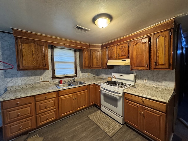 kitchen featuring dark hardwood / wood-style flooring, sink, light stone counters, and white gas stove