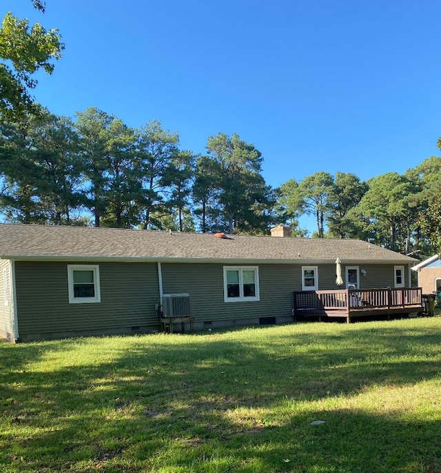 rear view of property featuring central AC unit, a wooden deck, and a lawn