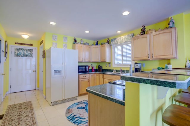 6180 Marsh Island Dr, Chincoteague, VA 23336 - kitchen featuring white fridge with ice dispenser, light brown cabinets, black microwave, a kitchen bar, and recessed lighting