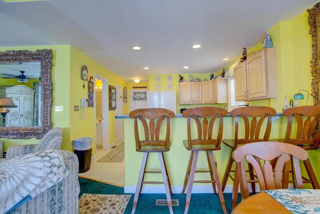 6180 Marsh Island Dr, Chincoteague, VA 23336 - kitchen featuring light brown cabinets, recessed lighting, ceiling fan, freestanding refrigerator, and a kitchen bar