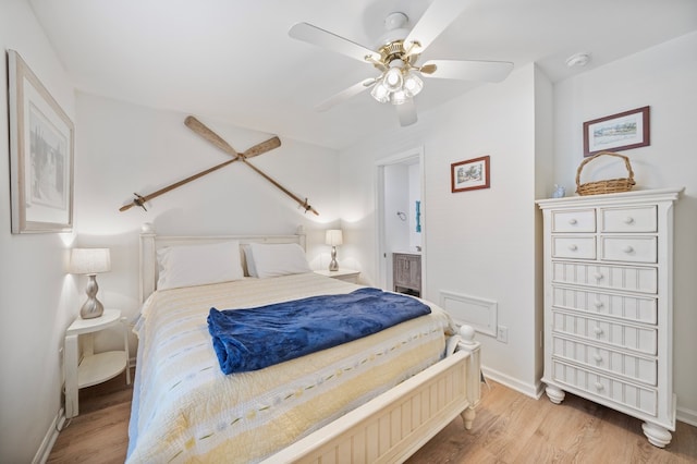 bedroom with light wood-type flooring, connected bathroom, baseboards, and a ceiling fan