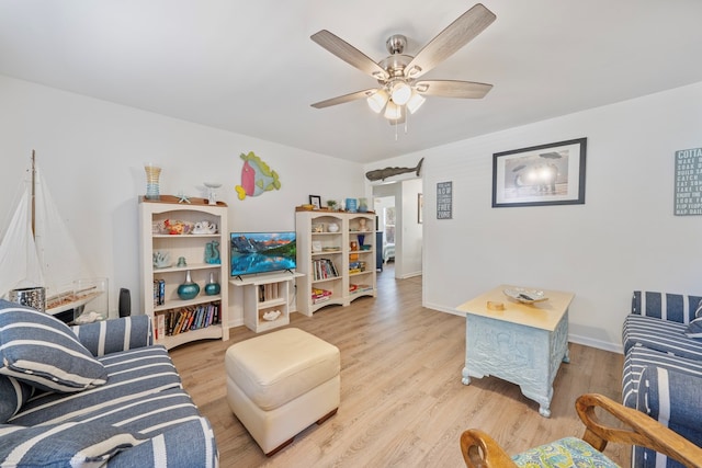 living area featuring ceiling fan, a barn door, baseboards, and light wood finished floors