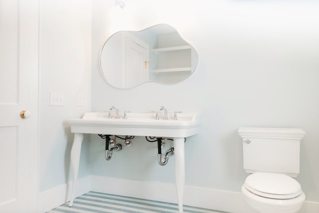 bathroom featuring baseboards and toilet