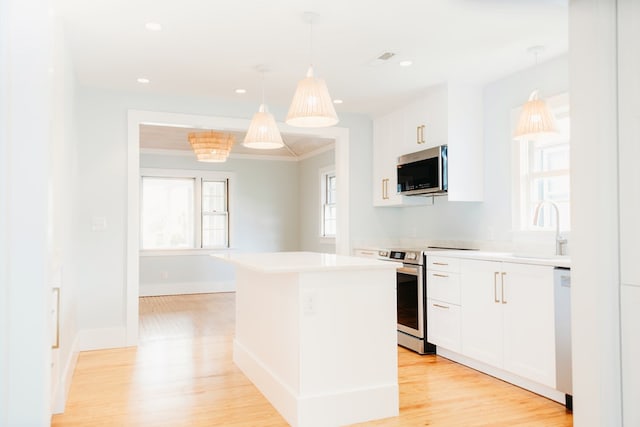 kitchen featuring a kitchen island, white cabinetry, appliances with stainless steel finishes, and a sink