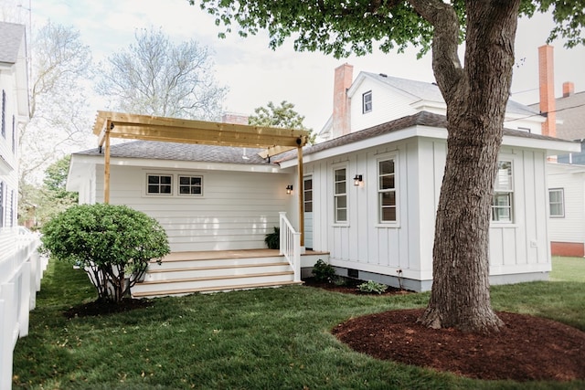 rear view of property featuring a lawn, board and batten siding, and a chimney