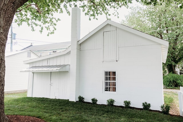 rear view of house featuring a lawn, concrete block siding, and a chimney