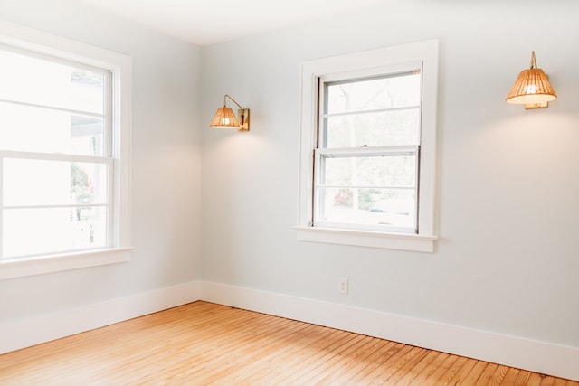 unfurnished room with baseboards, wood finished floors, and a wealth of natural light