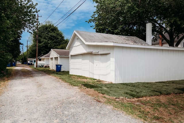view of side of property with an outdoor structure and gravel driveway