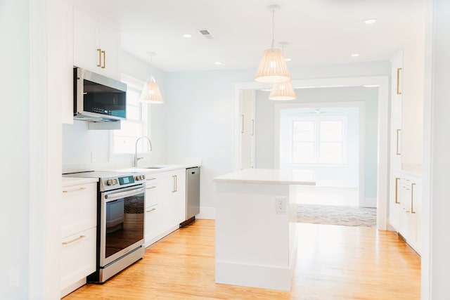 kitchen with a sink, light wood-style floors, stainless steel appliances, and white cabinetry