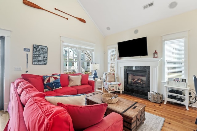 living area featuring wood finished floors, a fireplace, visible vents, and a wealth of natural light