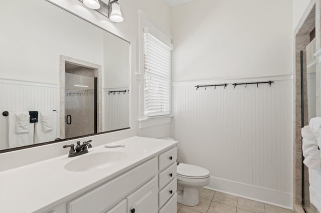 bathroom featuring a wainscoted wall, toilet, a shower stall, and tile patterned flooring