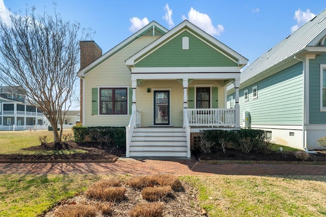 view of front of property featuring a front yard, covered porch, and a chimney