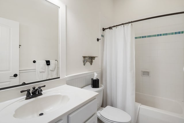 bathroom featuring wainscoting, toilet, shower / bath combo, and vanity