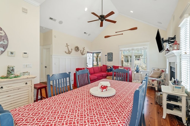 dining space featuring visible vents, a healthy amount of sunlight, a wainscoted wall, wood finished floors, and a ceiling fan