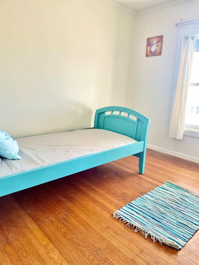 bedroom with hardwood / wood-style floors and crown molding