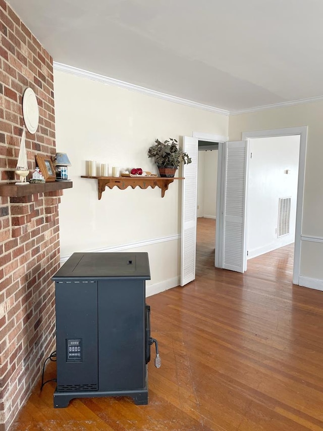 interior space with dark wood-type flooring, crown molding, and brick wall