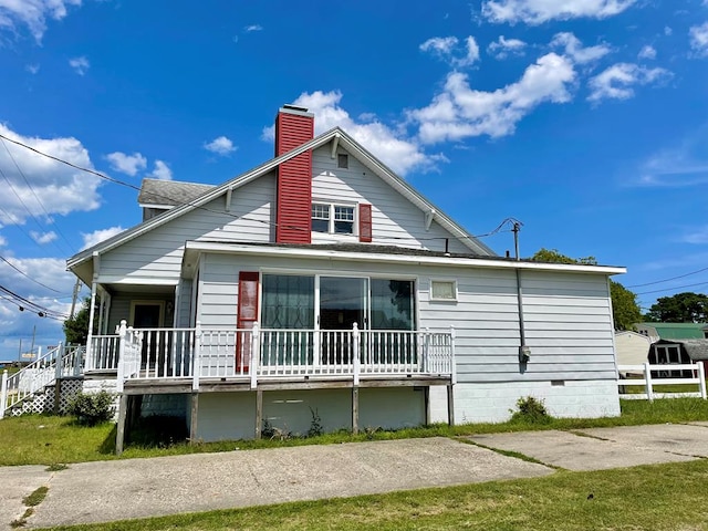 rear view of property featuring covered porch and a yard