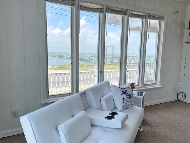 living room with plenty of natural light, a water view, and dark carpet