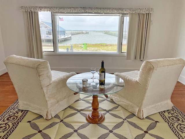 sitting room with hardwood / wood-style floors and a water view