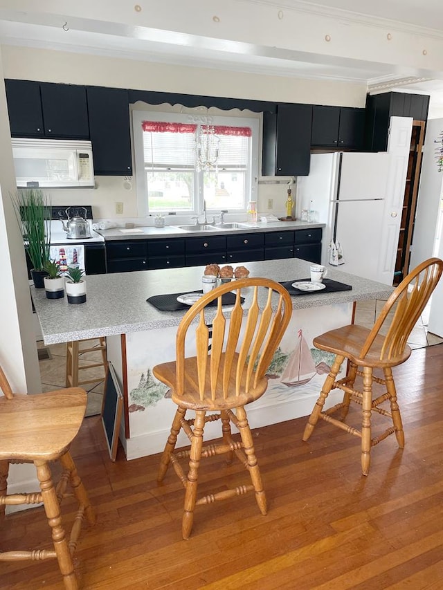 kitchen featuring light hardwood / wood-style floors, a kitchen island, white appliances, and sink