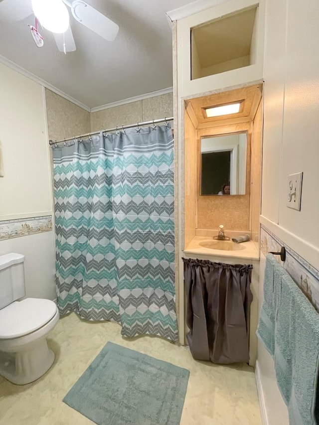 bathroom with vanity, ceiling fan, toilet, ornamental molding, and curtained shower