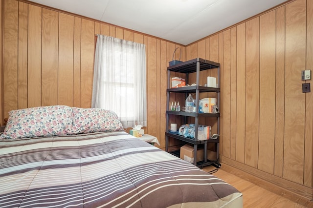 bedroom with wooden walls and light hardwood / wood-style floors