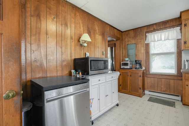 kitchen featuring white cabinets, crown molding, baseboard heating, and wooden walls