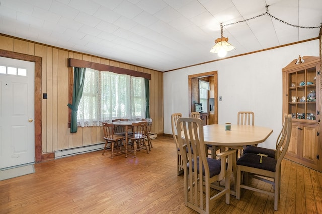 dining room featuring wood-type flooring, crown molding, and baseboard heating