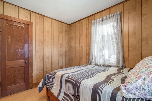 bedroom featuring wooden walls and light hardwood / wood-style flooring