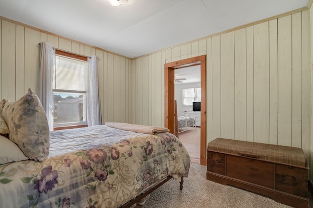 carpeted bedroom featuring wood walls