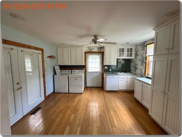 kitchen with light wood-type flooring, white dishwasher, washer and clothes dryer, ceiling fan, and white cabinets